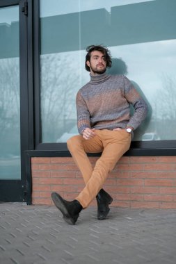 Ortasında çizgili süveter olan yakışıklı, siyah saçlı bir İtalyan. Yüksek kalite fotoğraf