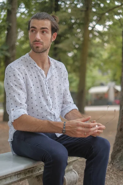 Parma 'daki Ducale parkındaki bankta oturan siyah tişörtlü yakışıklı İtalyan çocuk. Yüksek kalite fotoğraf