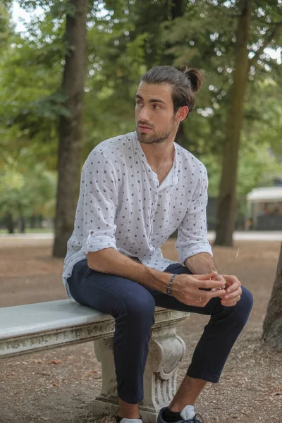 Parma 'daki Ducale parkındaki bankta oturan siyah tişörtlü yakışıklı İtalyan çocuk. Yüksek kalite fotoğraf