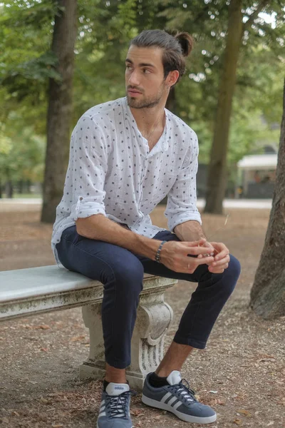 Parma 'daki Ducale parkındaki bankta oturan siyah tişörtlü yakışıklı İtalyan çocuk. Yüksek kalite fotoğraf