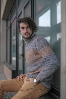 Ortasında çizgili süveter olan yakışıklı, siyah saçlı bir İtalyan. Yüksek kalite fotoğraf