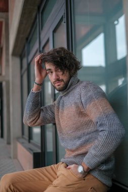 Ortasında çizgili süveter olan yakışıklı, siyah saçlı bir İtalyan. Yüksek kalite fotoğraf