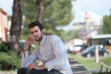 Güzel, siyah saçlı İtalyan çocuk ağaçların altında düşünceli bir şekilde oturuyor. Yüksek kalite fotoğraf