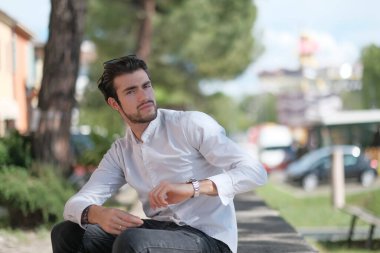 Güzel, siyah saçlı İtalyan çocuk ağaçların altında düşünceli bir şekilde oturuyor. Yüksek kalite fotoğraf