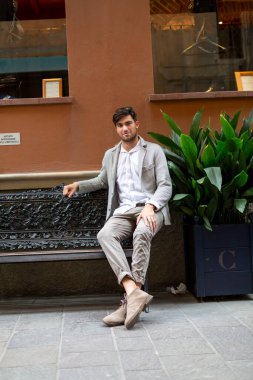 Güzel, siyah saçlı İtalyan adam zarif bir şekilde oturuyor. Yüksek kalite fotoğraf