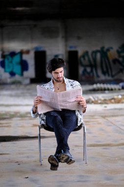 Güzel, siyah saçlı İtalyan çocuk terk edilmiş fabrikada gazete okuyor. Yüksek kalite fotoğraf