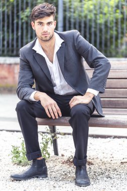 Tahta bankta oturan güzel siyah saçlı İtalyan çocuk. Yüksek kalite fotoğraf