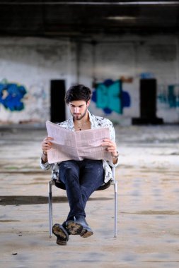 Güzel, siyah saçlı İtalyan çocuk terk edilmiş fabrikada gazete okuyor. Yüksek kalite fotoğraf