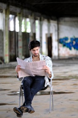 Güzel, siyah saçlı İtalyan çocuk terk edilmiş fabrikada gazete okuyor. Yüksek kalite fotoğraf