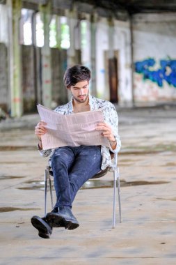 Güzel, siyah saçlı İtalyan çocuk terk edilmiş fabrikada gazete okuyor. Yüksek kalite fotoğraf