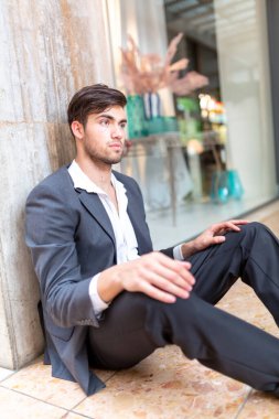 Güzel, siyah saçlı İtalyan çocuk şehir merkezinde yerde oturuyor. Yüksek kalite fotoğraf