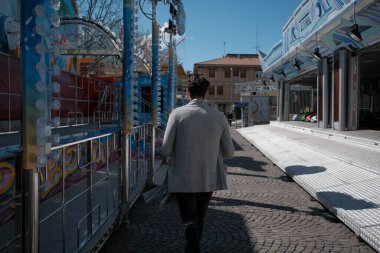 Güzel, siyah saçlı İtalyan çocuk terk edilmiş lunaparkta yürüyor. Yüksek kalite fotoğraf