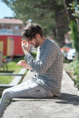 Beton duvarda oturan yakışıklı, siyah saçlı İtalyan çocuk. Yüksek kalite fotoğraf