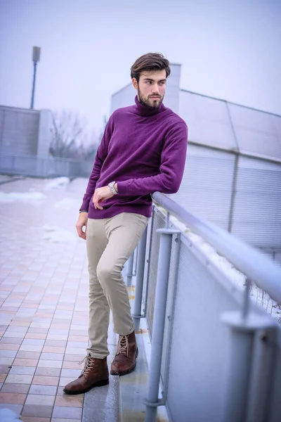 Yakışıklı, siyah saçlı, metal korkuluklara yaslanmış, kırmızı kazaklı bir İtalyan. Yüksek kalite fotoğraf