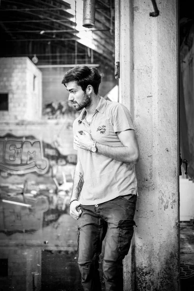 Dejenere olmuş terk edilmiş fabrikadaki yakışıklı siyah saçlı İtalyan adam. Yüksek kalite fotoğraf