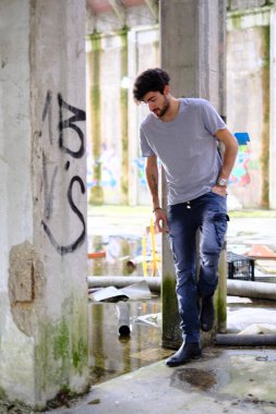 Dejenere olmuş terk edilmiş fabrikadaki yakışıklı siyah saçlı İtalyan adam. Yüksek kalite fotoğraf