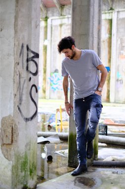 Dejenere olmuş terk edilmiş fabrikadaki yakışıklı siyah saçlı İtalyan adam. Yüksek kalite fotoğraf