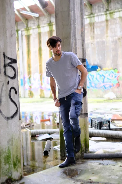 Dejenere olmuş terk edilmiş fabrikadaki yakışıklı siyah saçlı İtalyan adam. Yüksek kalite fotoğraf