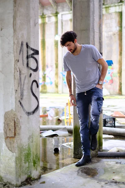 Dejenere olmuş terk edilmiş fabrikadaki yakışıklı siyah saçlı İtalyan adam. Yüksek kalite fotoğraf