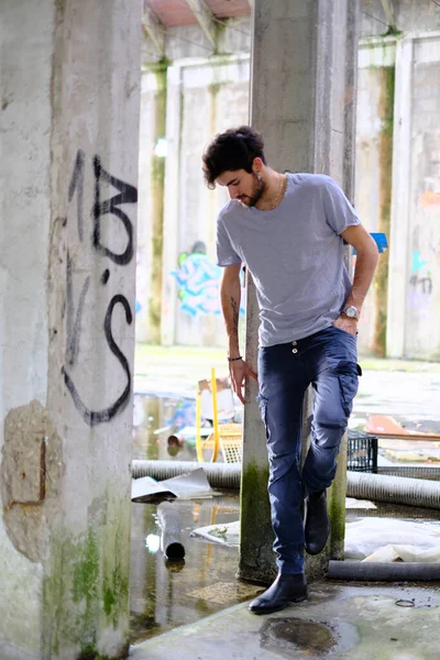 Dejenere olmuş terk edilmiş fabrikadaki yakışıklı siyah saçlı İtalyan adam. Yüksek kalite fotoğraf