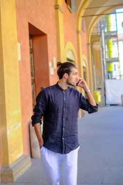 Yakışıklı, siyah saçlı İtalyan adam akıllı telefondan yürüyor ve konuşuyor. Yüksek kalite fotoğraf