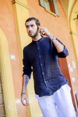 Yakışıklı, siyah saçlı İtalyan adam akıllı telefondan yürüyor ve konuşuyor. Yüksek kalite fotoğraf