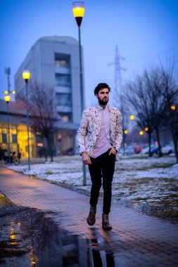 Yakışıklı, siyah saçlı İtalyan çocuk akşam şehir merkezinde yürüyor. Yüksek kalite fotoğraf