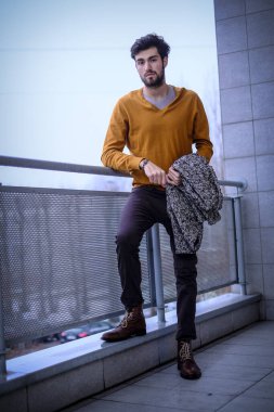 Uzun bir binanın çatısındaki yakışıklı, siyah saçlı adam. Yüksek kalite fotoğraf