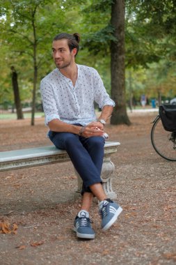 Beton duvarda oturan yakışıklı, siyah saçlı İtalyan çocuk. Yüksek kalite fotoğraf