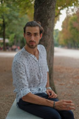 Beton duvarda oturan yakışıklı, siyah saçlı İtalyan çocuk. Yüksek kalite fotoğraf