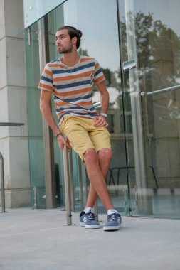 Yakışıklı, siyah saçlı bir İtalyan metal korkuluklarda oturuyor. Yüksek kalite fotoğraf