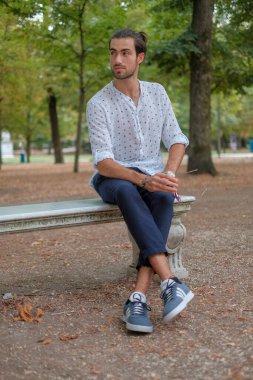 Beton duvarda oturan yakışıklı, siyah saçlı İtalyan çocuk. Yüksek kalite fotoğraf