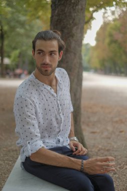 Beton duvarda oturan yakışıklı, siyah saçlı İtalyan çocuk. Yüksek kalite fotoğraf