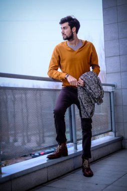 Uzun bir binanın çatısındaki yakışıklı, siyah saçlı adam. Yüksek kalite fotoğraf