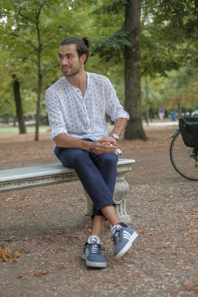 Beton duvarda oturan yakışıklı, siyah saçlı İtalyan çocuk. Yüksek kalite fotoğraf