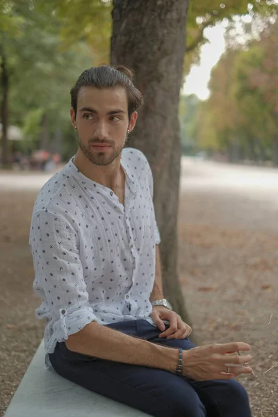 Beton duvarda oturan yakışıklı, siyah saçlı İtalyan çocuk. Yüksek kalite fotoğraf