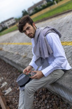 Yakışıklı, siyah saçlı İtalyan çocuk istasyondaki tren istasyonunda oturuyor. Yüksek kalite fotoğraf