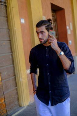 Ortadaki yakışıklı, siyah saçlı adam telefonu kullanıyor. Yüksek kalite fotoğraf