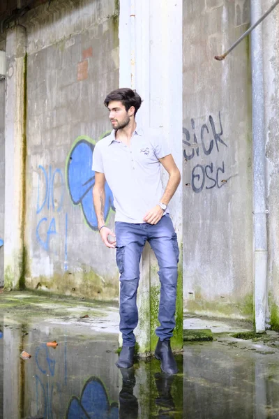 Dejenere olmuş terk edilmiş fabrikadaki yakışıklı siyah saçlı İtalyan adam. Yüksek kalite fotoğraf