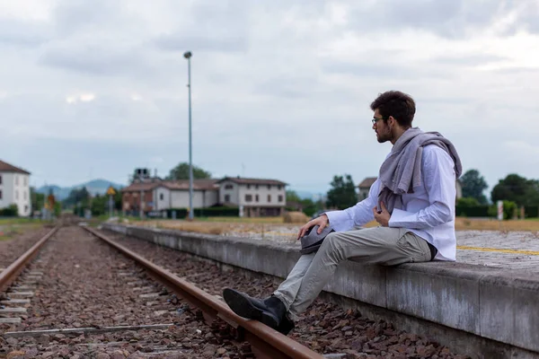 Yakışıklı, siyah saçlı İtalyan çocuk istasyondaki tren istasyonunda oturuyor. Yüksek kalite fotoğraf