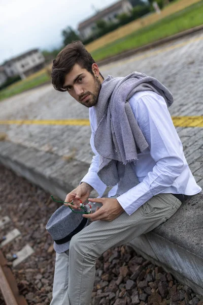 Yakışıklı, siyah saçlı İtalyan çocuk istasyondaki tren istasyonunda oturuyor. Yüksek kalite fotoğraf