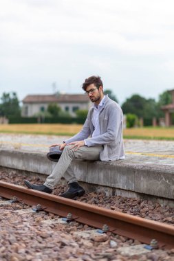 Yakışıklı, siyah saçlı İtalyan çocuk istasyondaki tren istasyonunda oturuyor. Yüksek kalite fotoğraf