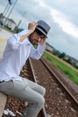 Yakışıklı, siyah saçlı İtalyan çocuk istasyondaki tren istasyonunda oturuyor. Yüksek kalite fotoğraf