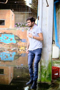 Dejenere olmuş terk edilmiş fabrikadaki yakışıklı siyah saçlı İtalyan adam. Yüksek kalite fotoğraf