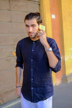 Ortadaki yakışıklı, siyah saçlı adam telefonu kullanıyor. Yüksek kalite fotoğraf