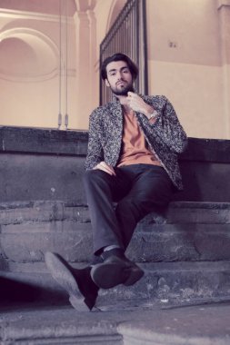 handsome Italian dark-haired boy sitting on the stairs of the Pilotta in Parma. High quality photo