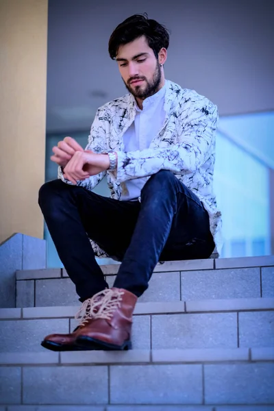 Yakışıklı, siyah saçlı, beyaz ceketli, merdivenlerde oturan adam. Yüksek kalite fotoğraf