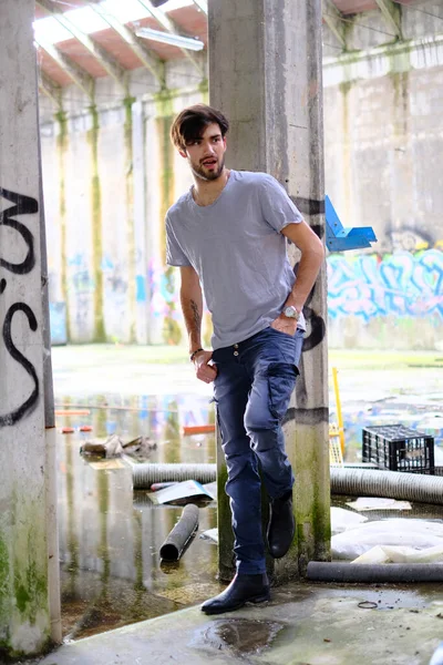 Dejenere olmuş terk edilmiş fabrikadaki yakışıklı siyah saçlı İtalyan adam. Yüksek kalite fotoğraf