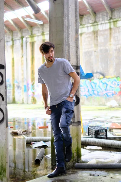 Dejenere olmuş terk edilmiş fabrikadaki yakışıklı siyah saçlı İtalyan adam. Yüksek kalite fotoğraf