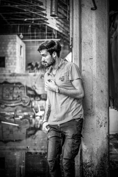 Dejenere olmuş terk edilmiş fabrikadaki yakışıklı siyah saçlı İtalyan adam. Yüksek kalite fotoğraf